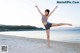 A woman standing on a beach with her arms outstretched.