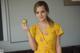 A woman in a yellow dress holding an apple.