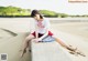 A woman sitting on a concrete bench on the beach.