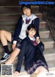 Two young women in school uniforms sitting on the steps.