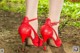 A close up of a woman's legs wearing red high heels.