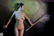 A nude woman holding a broom in her hand.