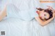 A woman laying on a bed in a white dress.