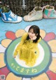 A young girl in a yellow dress sitting on the ground.