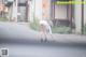 A woman in a white dress bending over on the street.