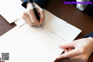 A person writing on a piece of paper with a pen.